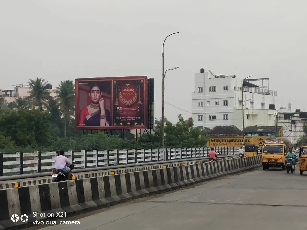 Hoarding beside the Amaravathi Bridge road with traffic passing